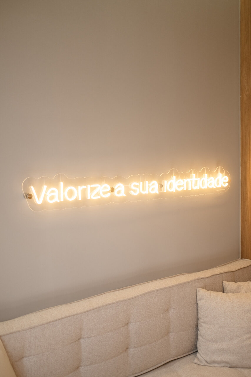 Sala com sofá e letreiro neon Valorize a sua identidade
